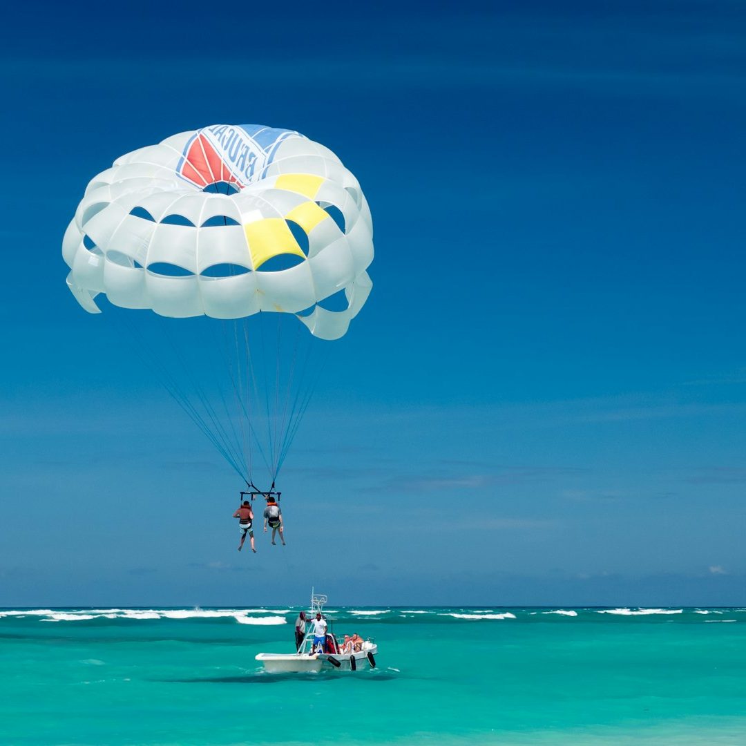 two person riding parachute near beach