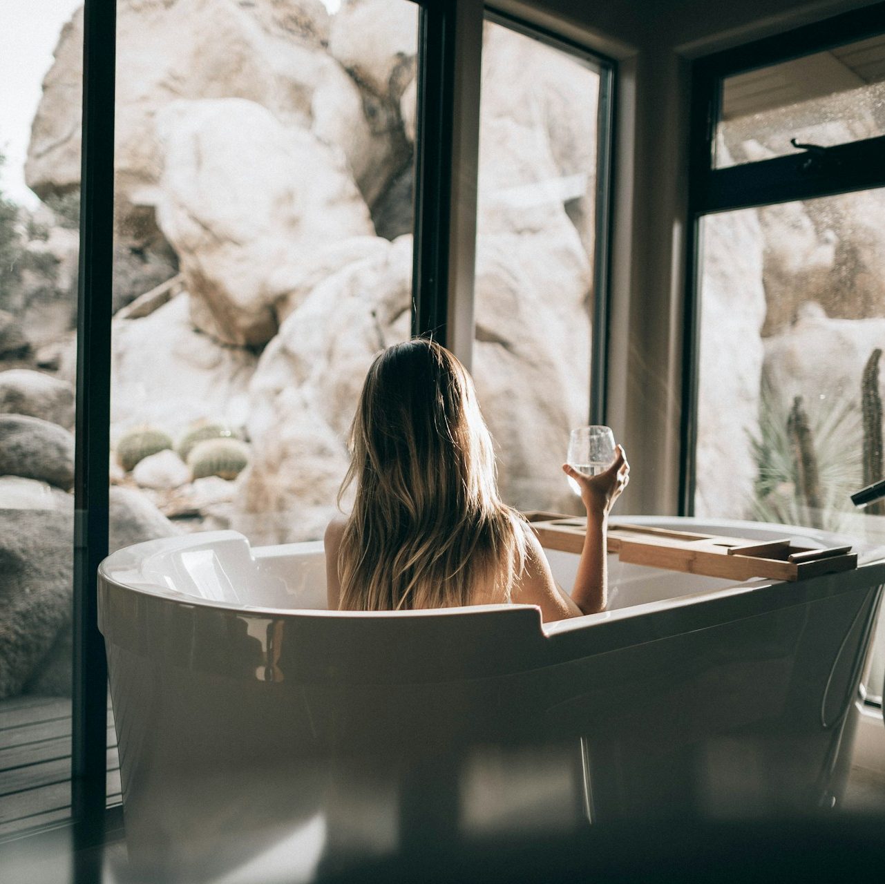 woman in white bathtub holding clear drinking glass